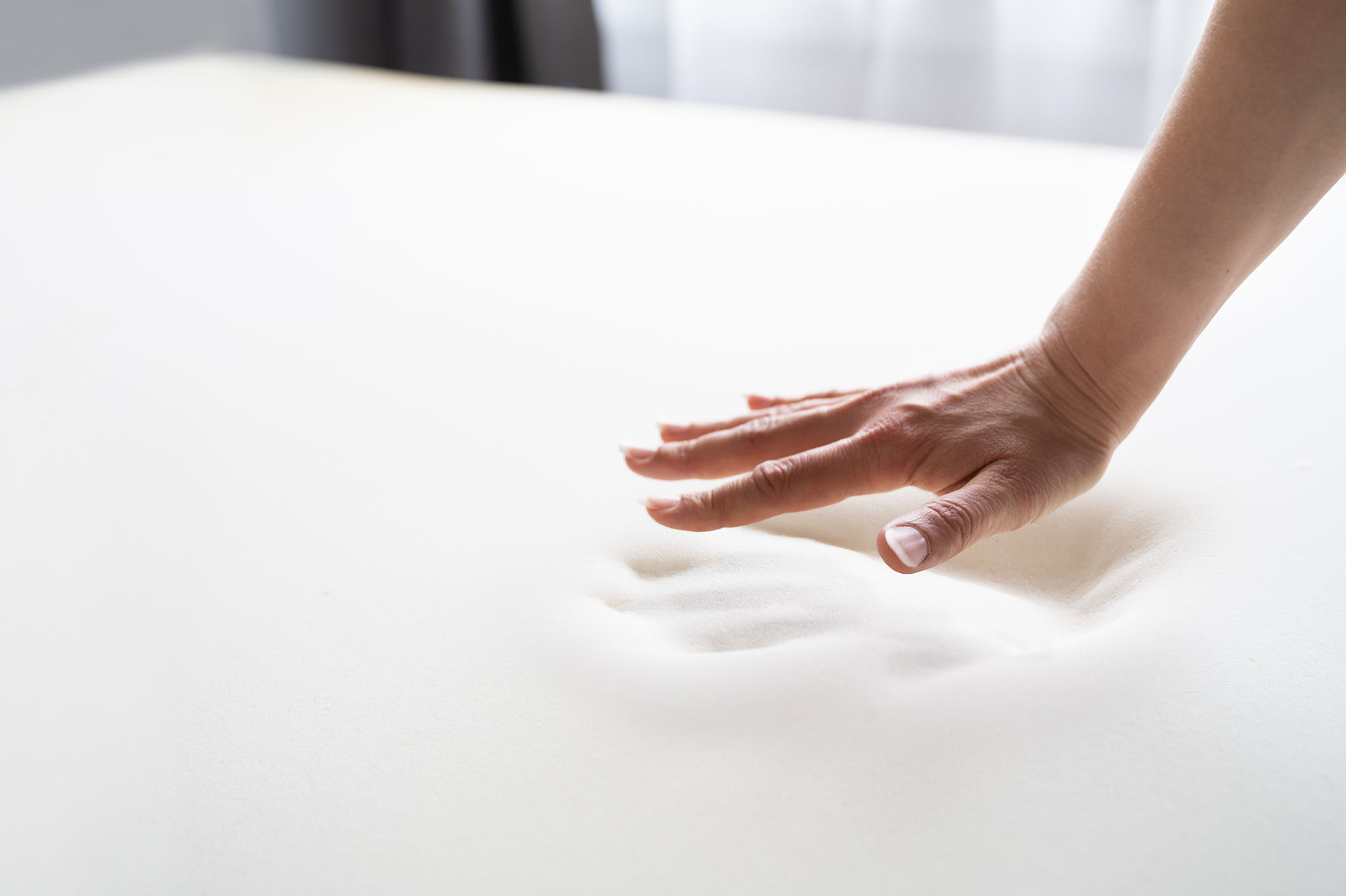 Hand pressing down on memory foam mattress