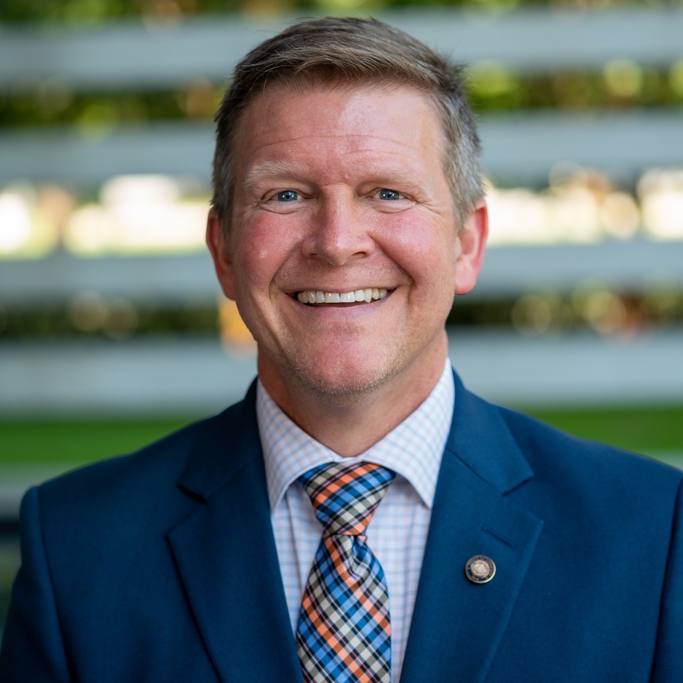 Chris Stelly headshot, he wears a navy blue suit 