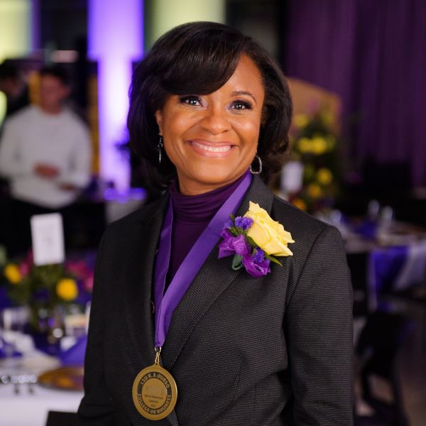 Joaneane Smith is wearing suit and medal around her neck. 