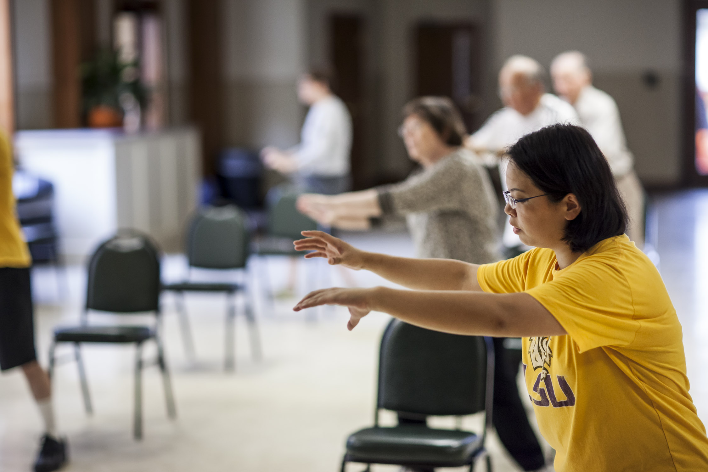 woman in yellow shirt and others doing tai chi