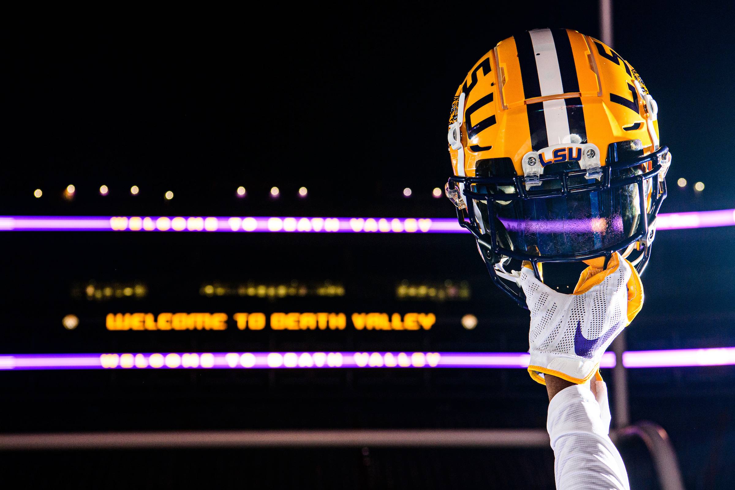 Photo of a hand holding up a LSU football helmet inside of Tiger Stadium