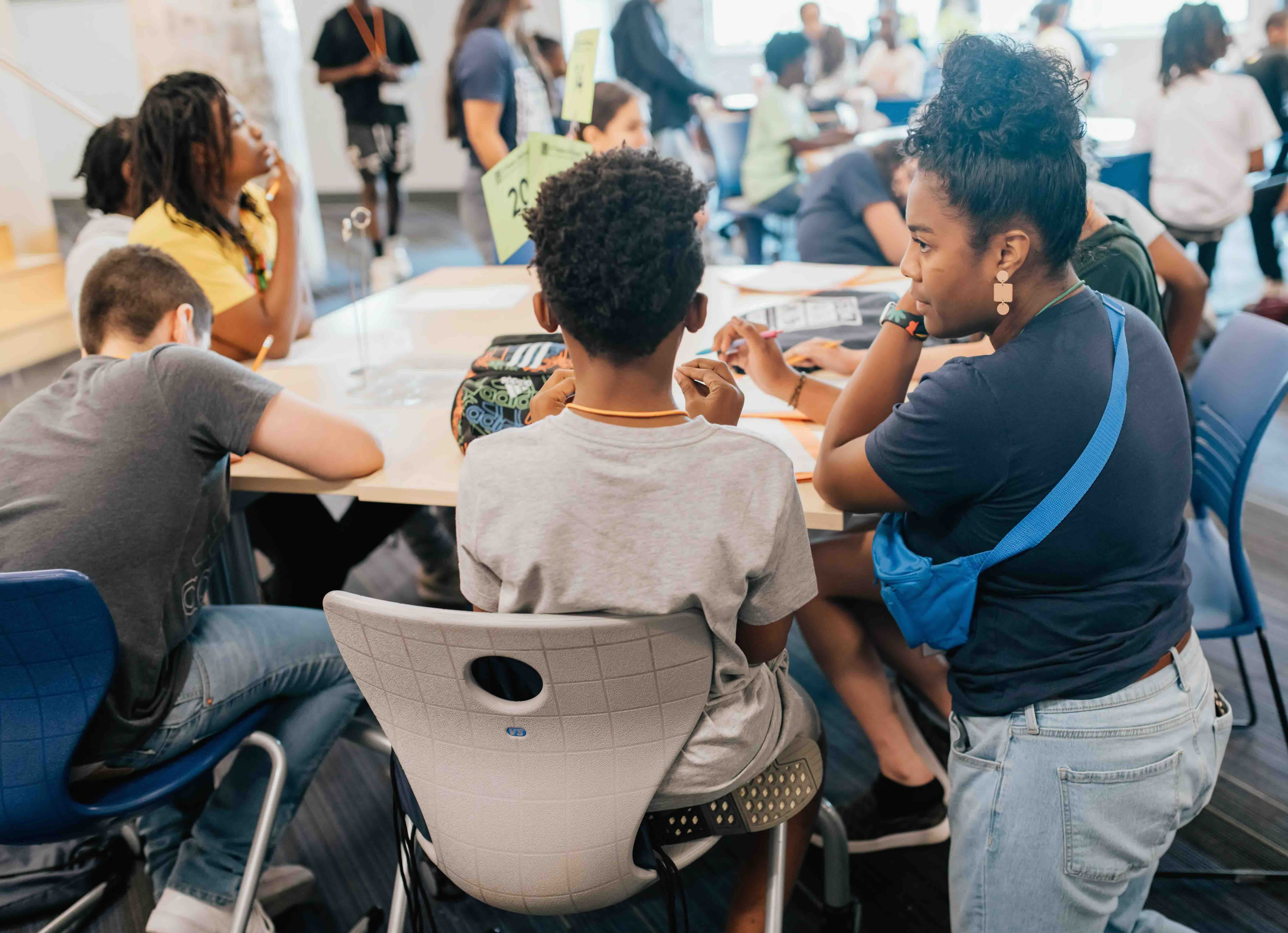 Tailenn engaging with students at their table.